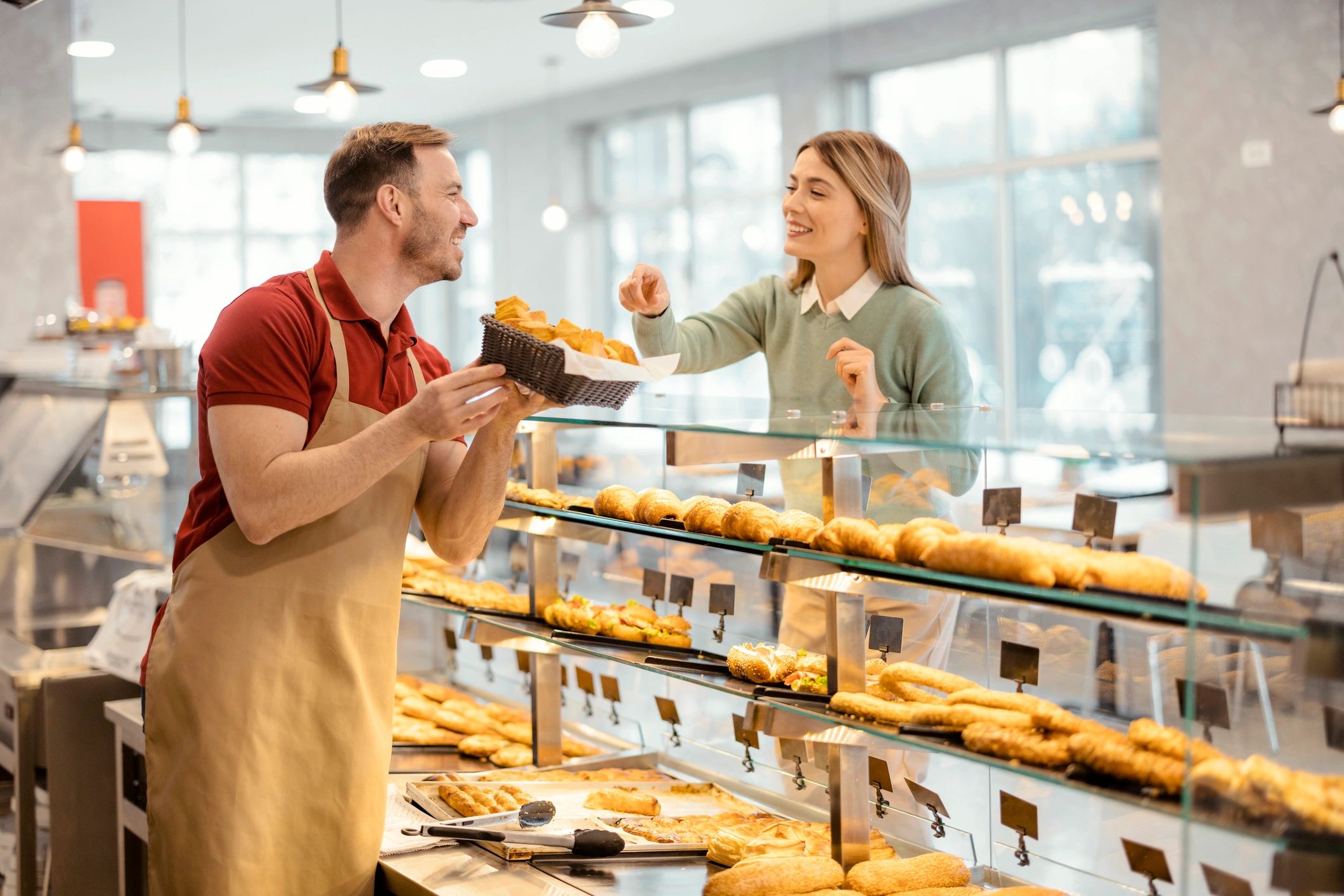 Bakery staff handing a pastry to a customer at the counter