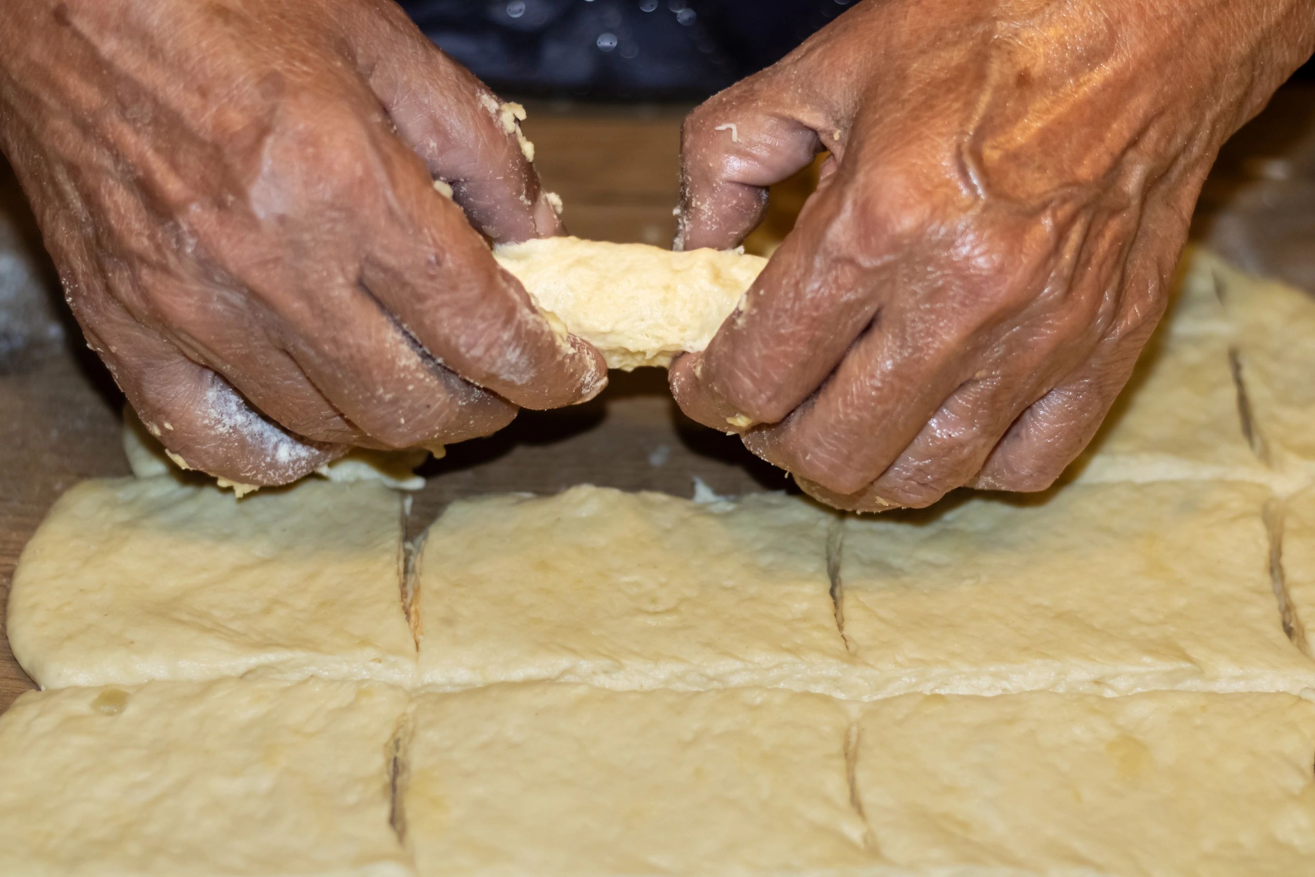 Hands shaping dough pieces on a floured work surface